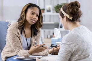 A Black woman is seen talking with a white woman.