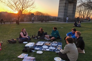 Jewish students at Brown University share a meal in a park as the sun sets.