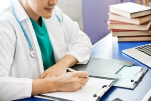 Doctor writing on clipboard