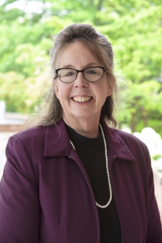 Athens State interim president Catherine Wehlburg, a white woman wearing interestingly shaped eyeglasses and a purple jacket.