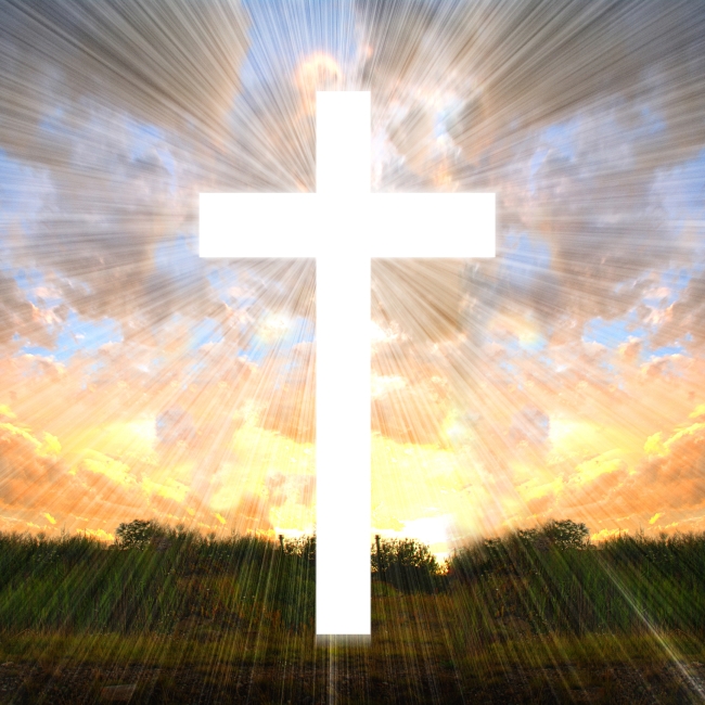 A white cross, lit by sunlight, against a pink and blue sky. 